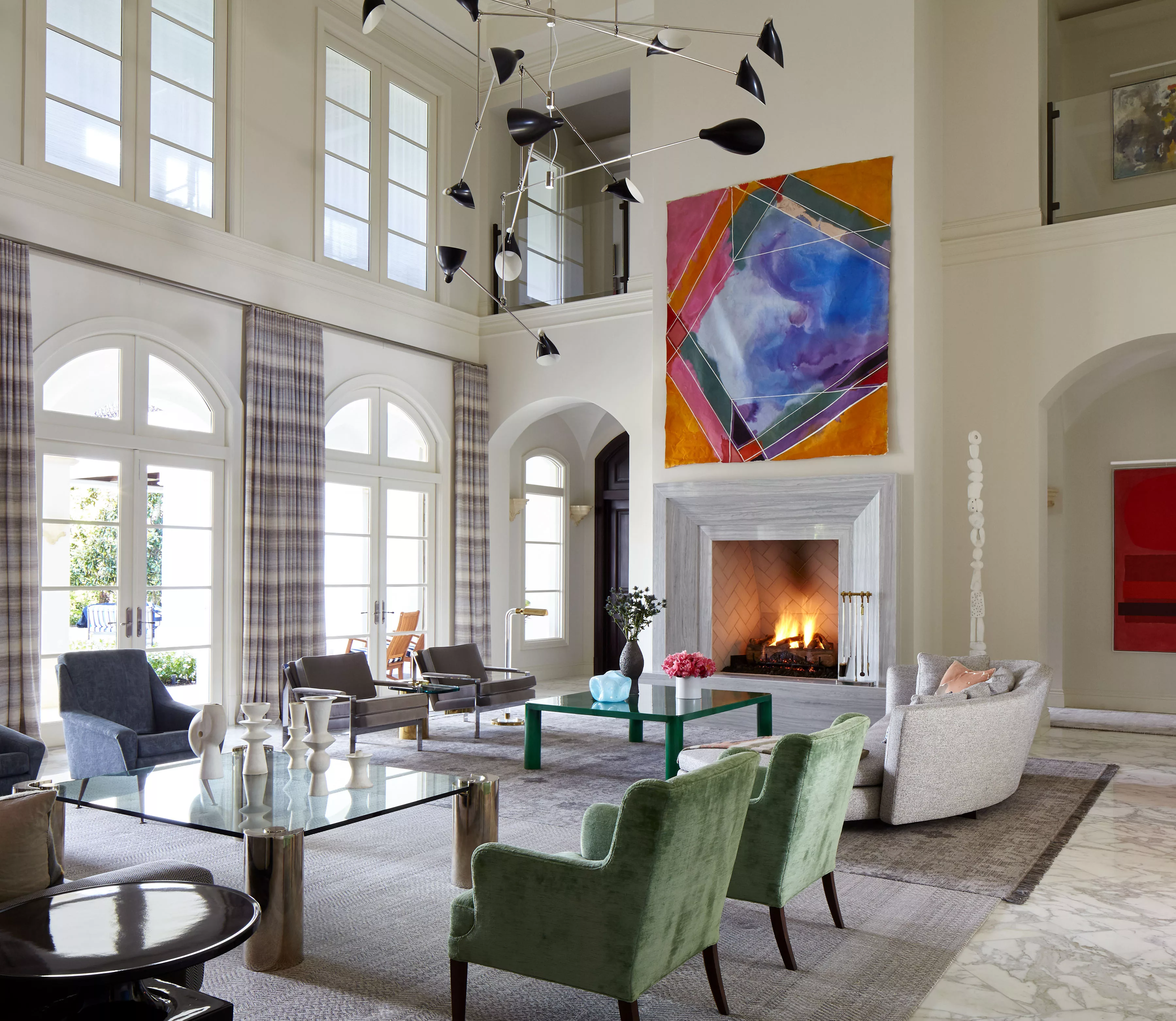 Florida Estate Spacious Living Room with two tables and multiple chairs in different colors in front of a Big Fireplace.