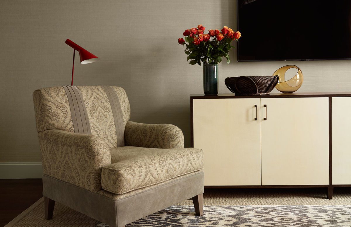 An Armchair in warm tones against a wooden desk with a TV