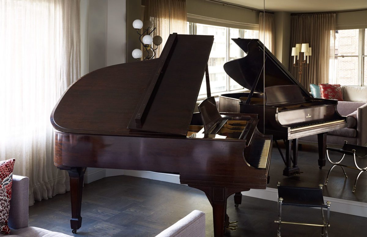 A Wooden Piano next to a Full-Lenght Mirror Panel on the Wall