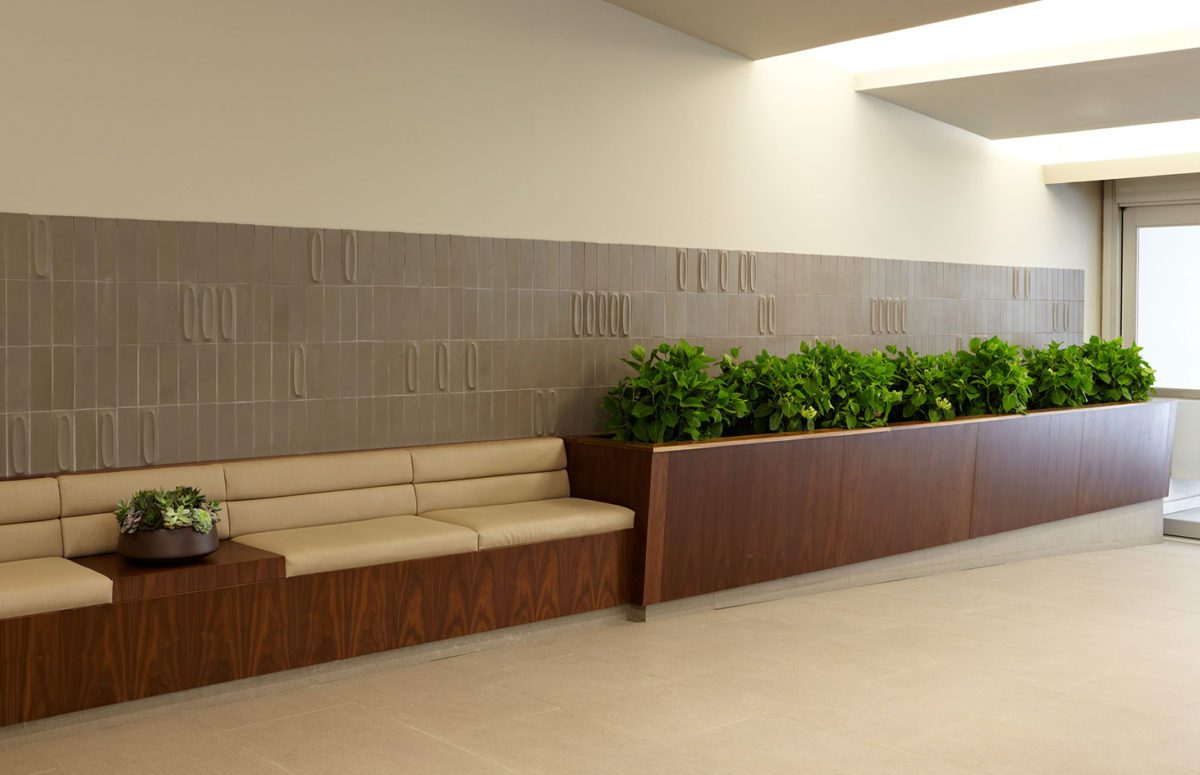 A Corridor with A Large Cushioned Bench and A Wooden Flowerpot