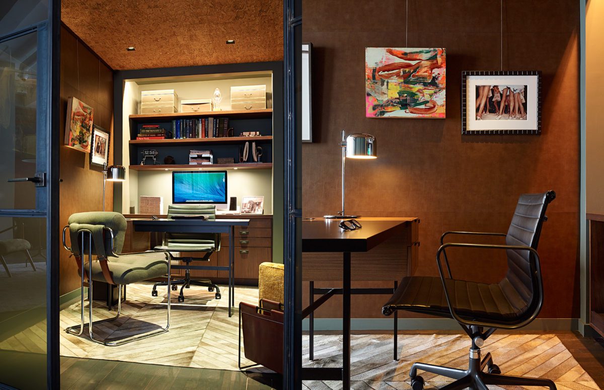 Office area with shelves, office desk with a table lamp, an office chair, an abstract painting and a photo on the wall