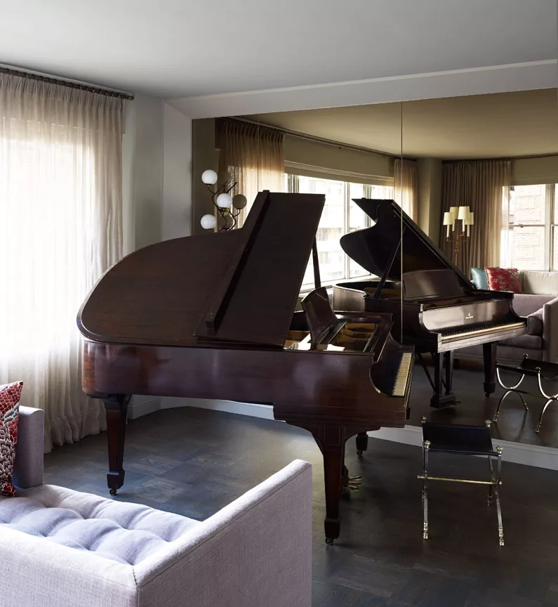 A Wooden Piano next to a Full-Lenght Mirror Panel on the Wall