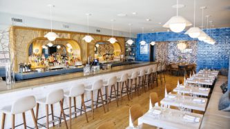 Rosie's Restaurant | Blue, white, and beige Interior Design, Large Bar Counter and A Dining Area to the Right.