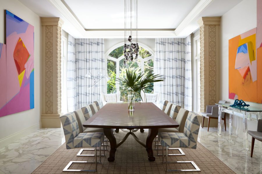 Spacious Dining Room with Big Wooden Table In the Middle of the Room and two Abstract Paintings on the Both Sides