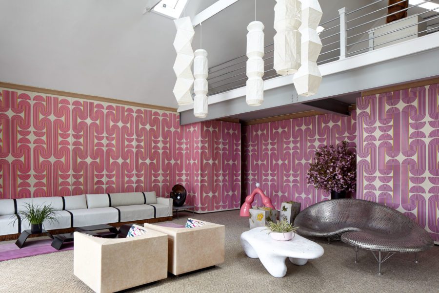 Sculptural Furniture in Different Colors and Shapes and a big Pink Wallpaper with Repetitive Patterns