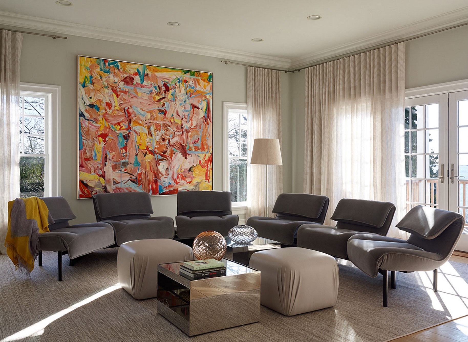 View of a Living room with Grey Chairs Organized in a Circle and a Large Abstract Painting.