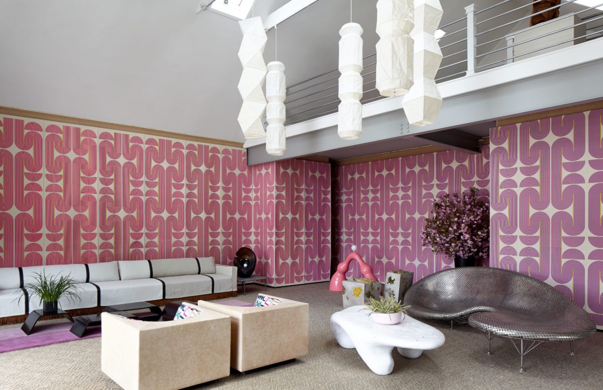 Sculptural Furniture in Different Colors and Shapes and a big Pink Wallpaper with Repetitive Patterns