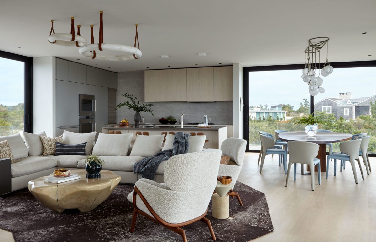 Spacious Kitchen in Brown and Grey Shades, A Dining Table next to a Huge Window, and L-Shaped Cozy White Sofa
