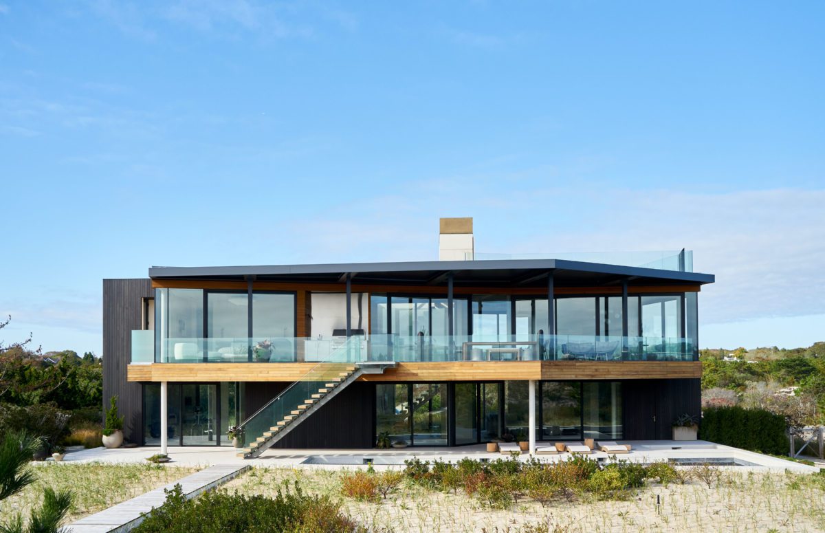 Outdoor view of a two-floor residence with crystal railing and big windows