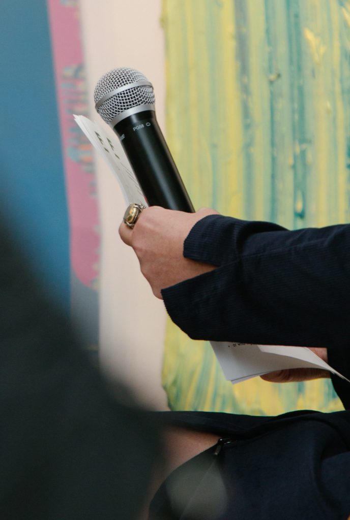 A Hand Holding a Microphone and Papers at an Event