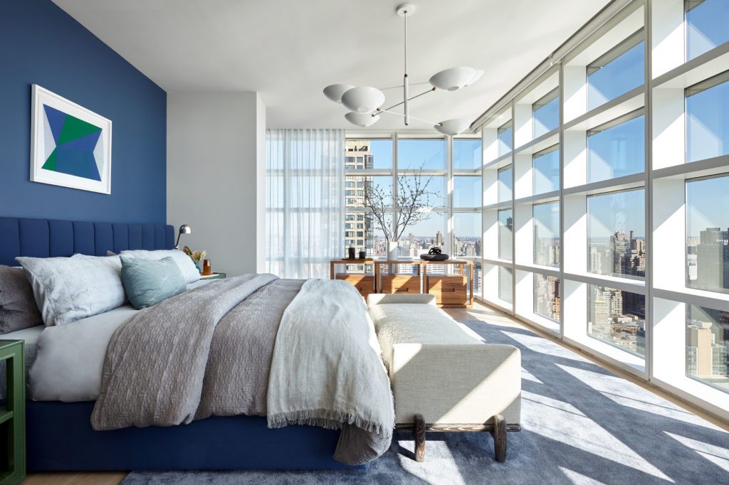 Wide Bedroom with Blue and White Walls and Big White Framed Windows with Views of the City