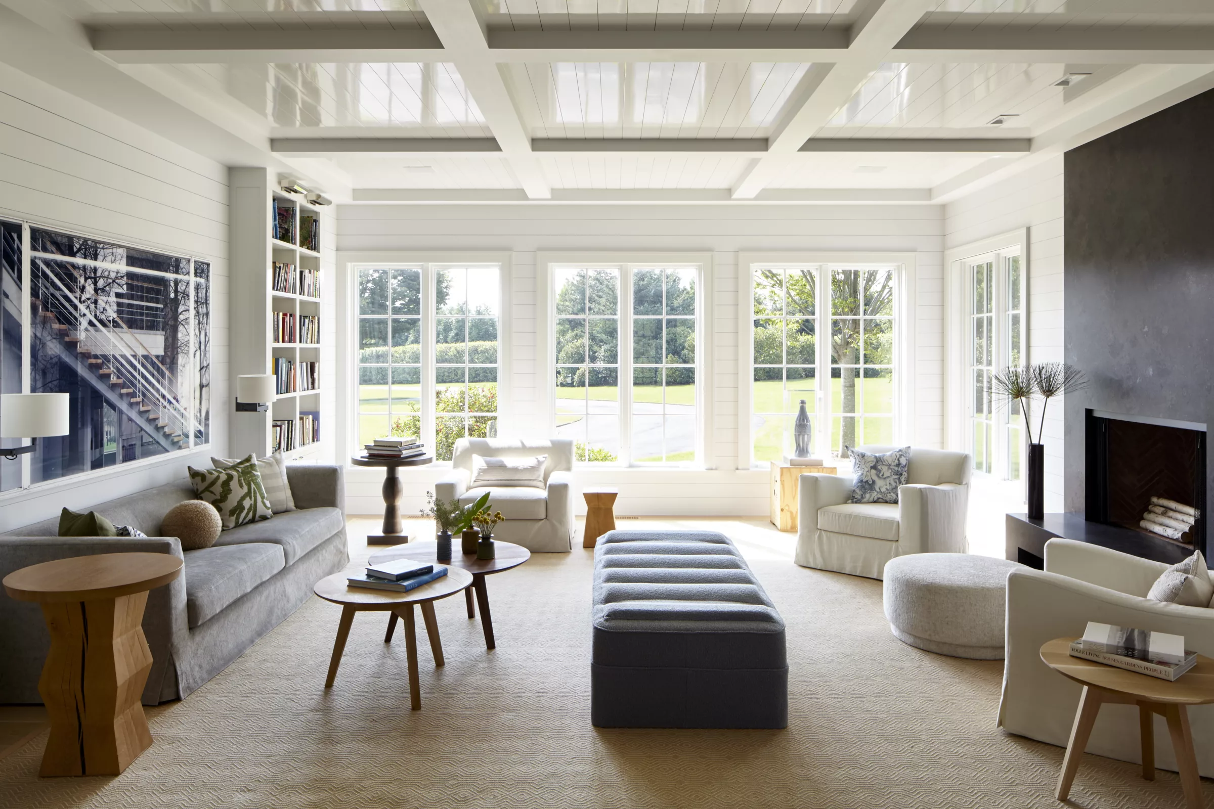 living room with glossy white ceiling and two furniture groupings with a center ottoman